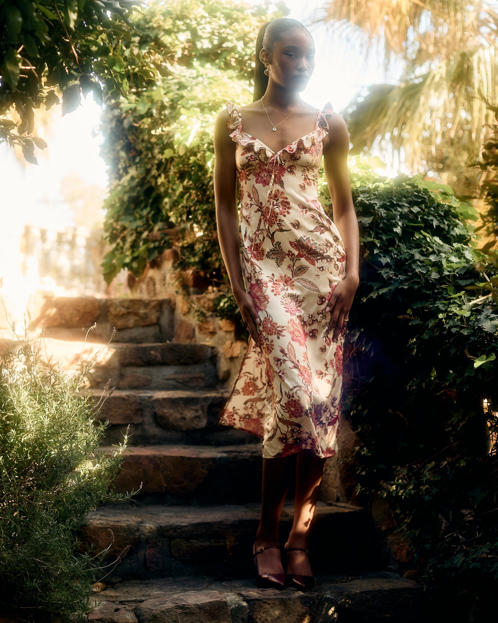 Florence Dress in the red and pink floral print, standing on garden steps in Cape Town
