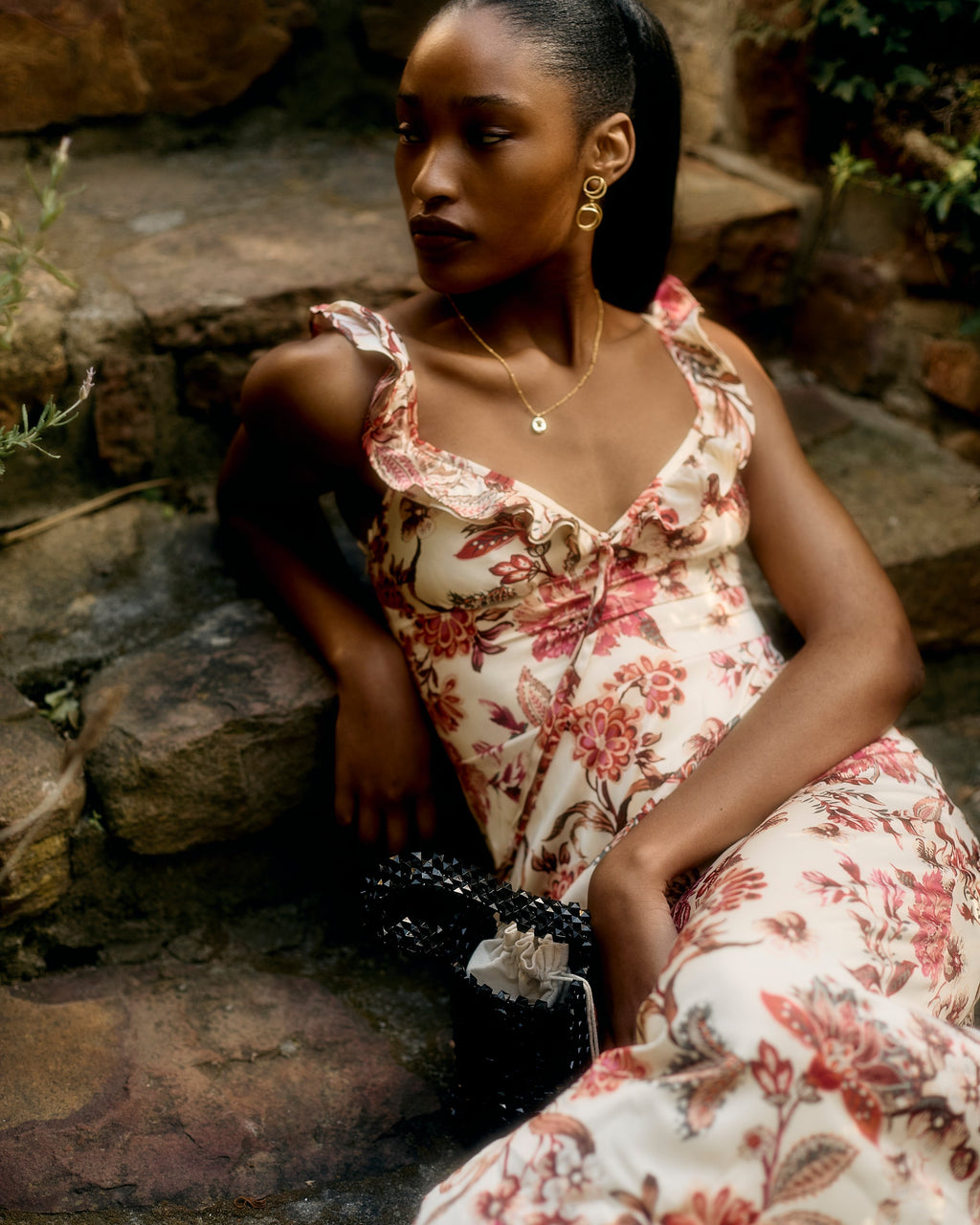 Florence Dress in the red and pink floral print, sitting on stone steps