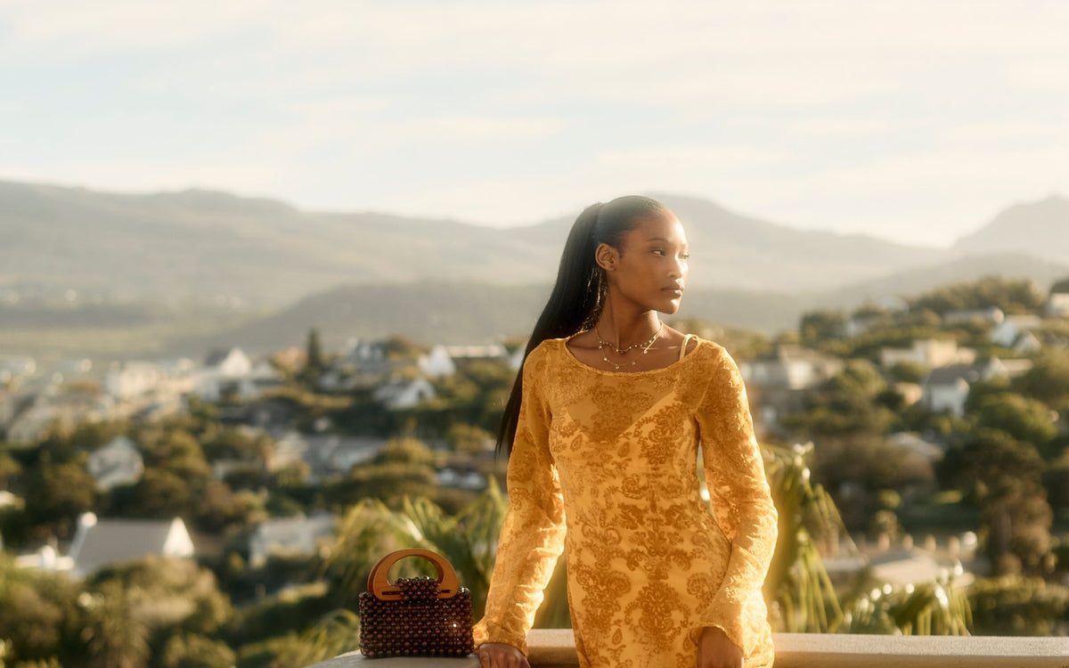 Reiko Dress in yellow velvet lace on a terrace overlooking Cape Town