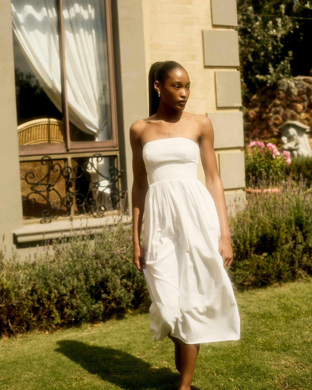 Juliette Dress in white linen, walking across a lawn