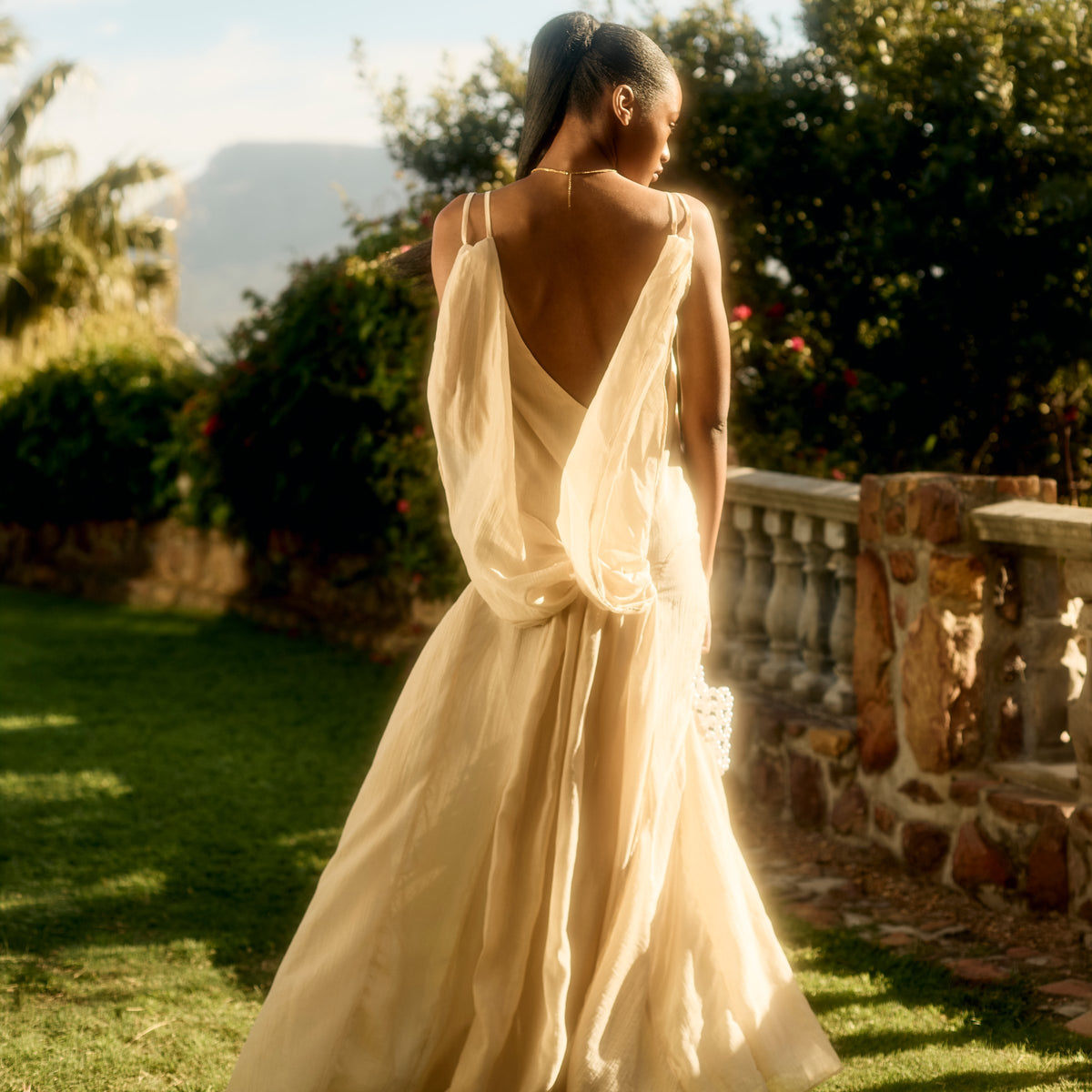 Sienna Dress in pearl seen from the back in a garden