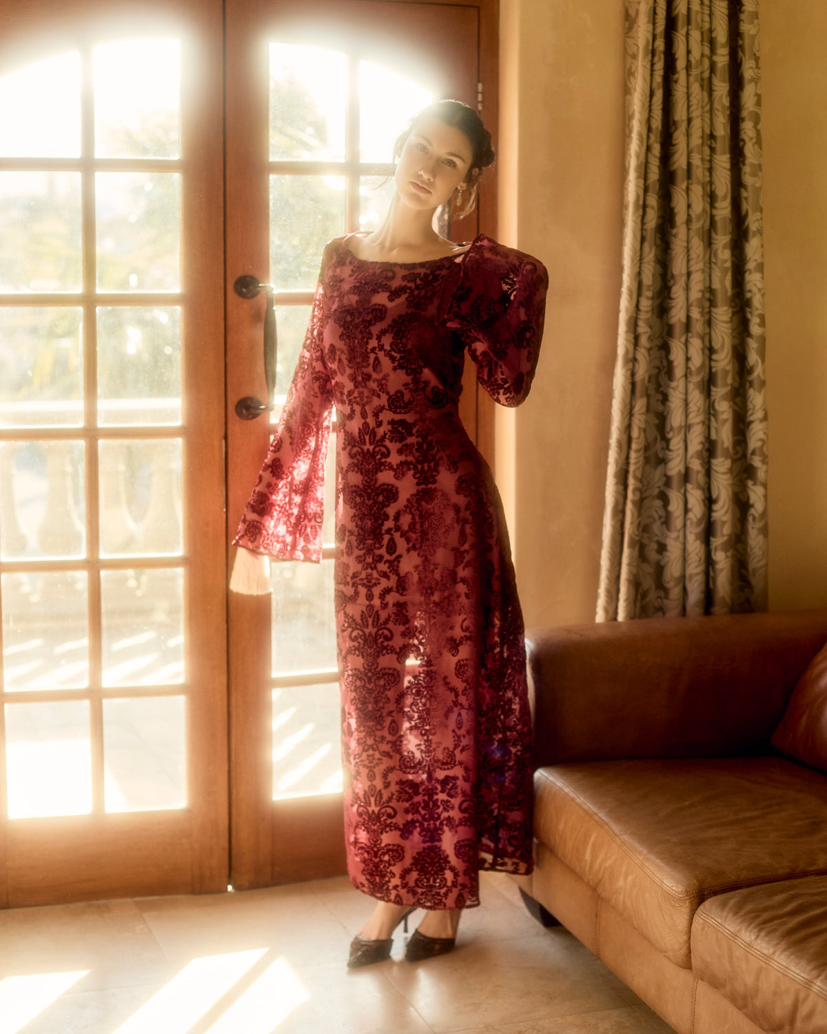 Reiko Dress in red, standing by glass doors